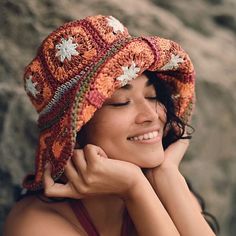 a woman with her eyes closed wearing a crocheted hat