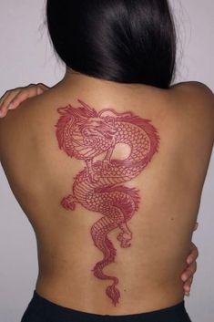 the back of a woman's body with a red dragon tattoo on her shoulder