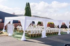 an outdoor wedding set up with white linens and draping for the ceremony