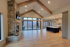 a large open floor plan living room with wood floors and stone fireplace in the center