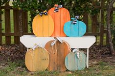 some pumpkins are sitting on top of a white bench in front of a fence