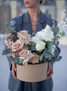 a woman holding a flower arrangement in her hands