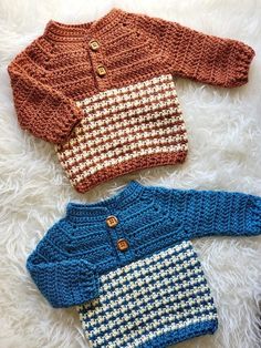 three knitted sweaters laying on top of a white rug