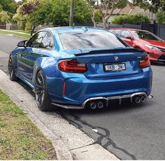 the rear end of a blue bmw car parked on the side of the road in front of other cars