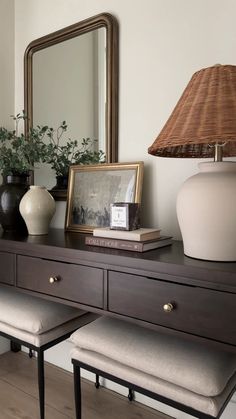 a table with two vases and a lamp on it next to a mirror in a room