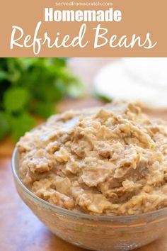 homemade refried beans in a glass bowl on a wooden table with parsley behind it