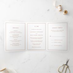 the wedding stationery is laid out on a marble table with scissors and other items