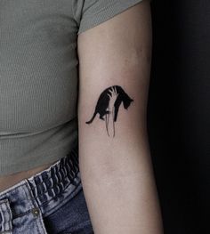 a woman's arm with a small black and white cat tattoo on the left upper arm