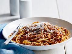 a plate of spaghetti with meat sauce and parmesan cheese on top, next to a cup of coffee