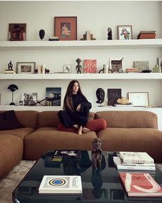 a woman sitting on top of a couch in a living room next to a coffee table