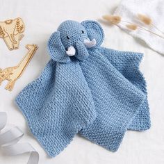 a blue knitted elephant blanket next to a wooden brooch and two other items