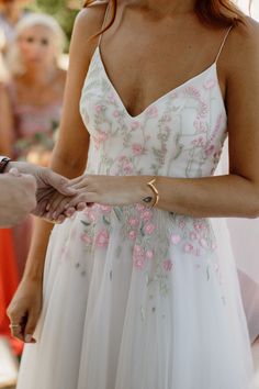 a woman in a white dress holding the hand of another person