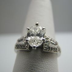 "For sale: (1) d863 Stunning 14k White Gold Engagement Ring PLEASE READ ENTIRE DESCRIPTION BEFORE PURCHASING Pre-owned item. Good condition. Please see pictures for details. Sold as is, as seen on pictures. This ring contains 35 diamonds. The centerpiece is oval cut; two diamonds are baguette cut; 32 are round cut. This ring is stamped on the inside of the shank. Has GIA Certificate on center oval diamond. See picture for details. Specifics: 14k White gold Diamonds: 1.40TCW Size: 6.75 (U.S.) Wid Classic Collectible Diamond Ring With Vvs Clarity, Exquisite Platinum Diamond Ring Hallmarked, Exquisite Platinum Hallmarked Diamond Ring, Classic Collectible Diamond Ring With Center Stone, Luxury Hallmarked Oval Diamond Ring, Oval Brilliant Cut Diamond Ring Collectible, Oval Brilliant Cut Diamond Ring For Collectors, Classic Rings With Diamond Accents For Collectors, Classic Collectible Rings With Diamond Accents