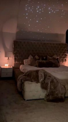 a large bed in a room with lights on the wall and a teddy bear laying on it's side