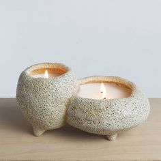 two white candles sitting on top of a wooden table