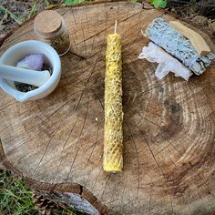 a candle sitting on top of a piece of wood next to a bowl and spoon