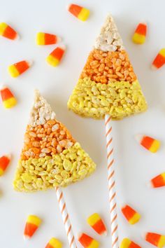 candy corn and candy canes are arranged in the shape of triangle shaped trees on a white surface