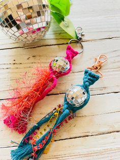 two disco ball keychains on a wooden table next to a mirror ornament