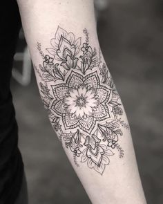 a black and white photo of a flower tattoo on the arm