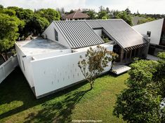 an aerial view of a modern house in the middle of a lush green area with trees