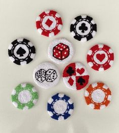 six poker chips are arranged in the shape of hearts and spades on a white surface