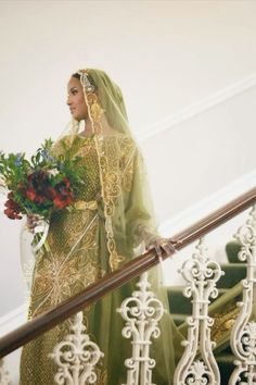 a woman in a green dress is walking down the stairs with flowers on her head