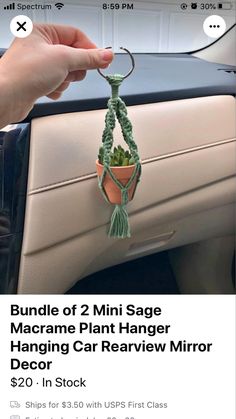 a hand holding a small potted plant hanging from a car door hanger with the words bundle of 2 mini sage macrame plant hanger hanging car rearview mirror decor $ 20 in stock