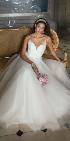 a woman in a white wedding dress sitting on a gold couch with bubbles floating around her