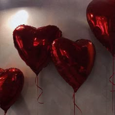 three red heart shaped balloons hanging on a wall