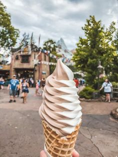 someone holding up an ice cream cone with people in the background