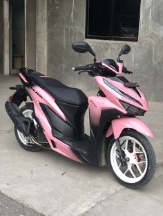 a pink and black scooter parked in front of a building with concrete walls