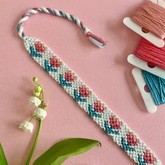 three spools of thread are sitting on a pink surface next to a flower