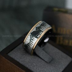 a ring with an eagle on it sitting in a wooden box next to a book