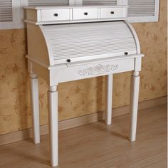 a white desk with drawers on it in front of a wallpapered wall and wooden floor