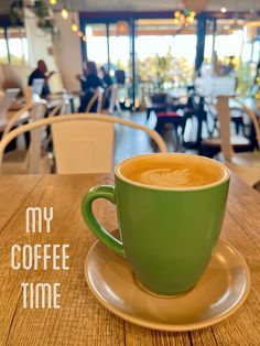 a green coffee cup sitting on top of a saucer next to a wooden table