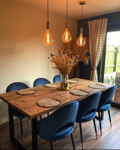 a dining room table with blue chairs and hanging lights