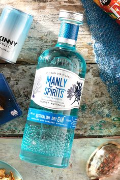 a bottle of manly spirits gin next to some snacks and drinks on a wooden table