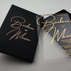 an open black and gold wedding card on a white surface with the words barbara and mario printed on it