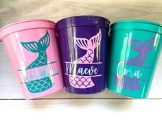 three colorful cups with mermaid designs on them