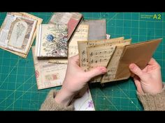 a person holding an open book on top of a table with lots of old music sheets