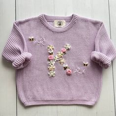 a pink sweater with flowers on it and a button in the middle that says, i love you