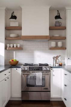 a stove top oven sitting inside of a kitchen next to white cabinets and open shelves