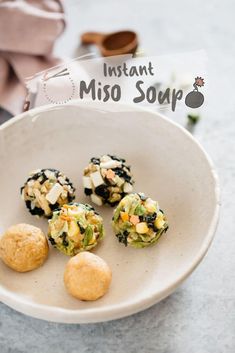 four small food items in a white bowl on a marble counter top next to a napkin and spoon