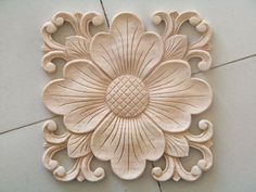 an intricately carved piece of wood on the floor with white tiles in the background