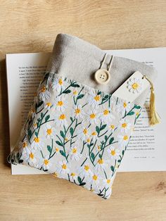 a book laying on top of a wooden table next to a bag with a button