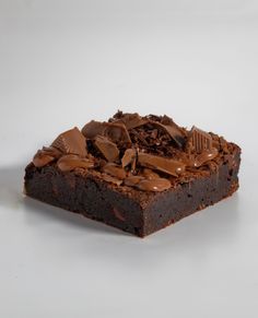 a piece of brownie with chocolate frosting on it sitting on a white surface