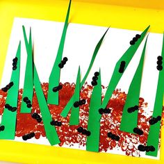 an art project made out of paper with grass and blackberries on it in front of a yellow frame