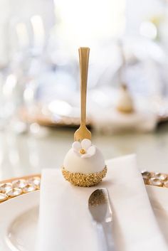 a white plate topped with a cake covered in icing and a gold fork on top of it