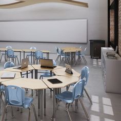 an empty classroom with blue chairs and laptops