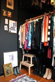 a closet with clothes and shoes hanging on the wall next to a wooden bench in front of it